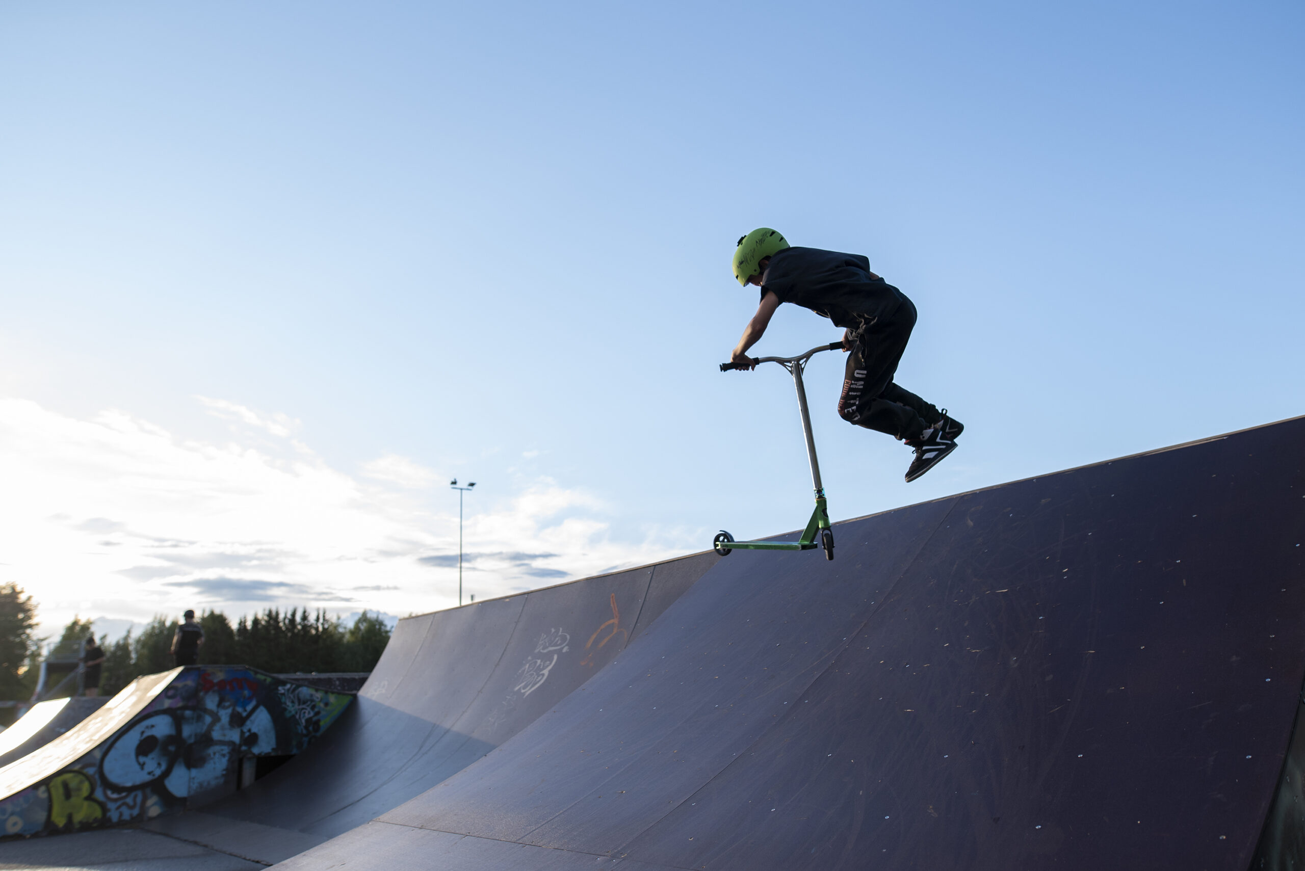 Lapsi skeittaa rampilla, taustalla sininen taivas