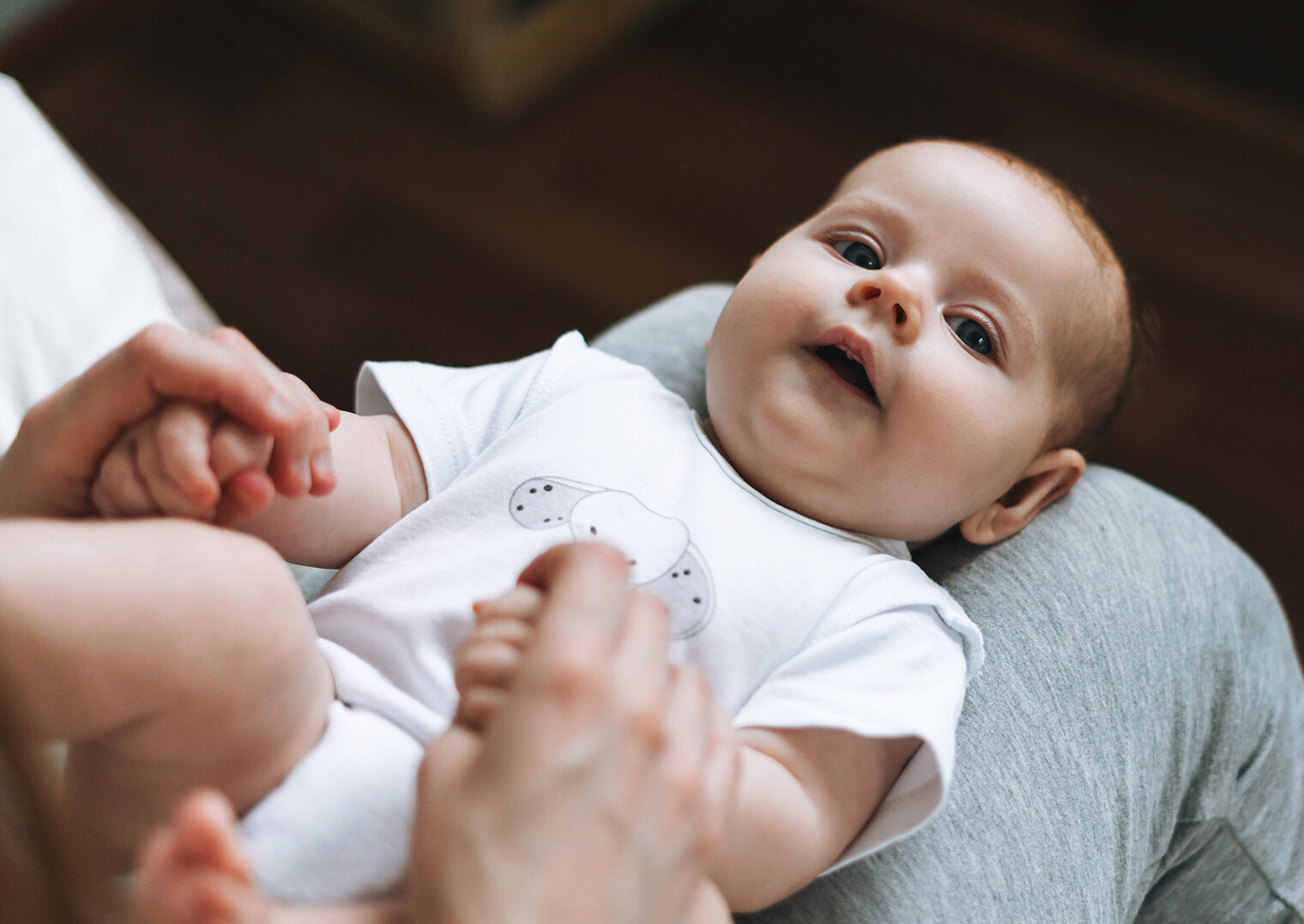 Young mother having fun with cute baby girl on her knees sitting on the bed at home, love emotion